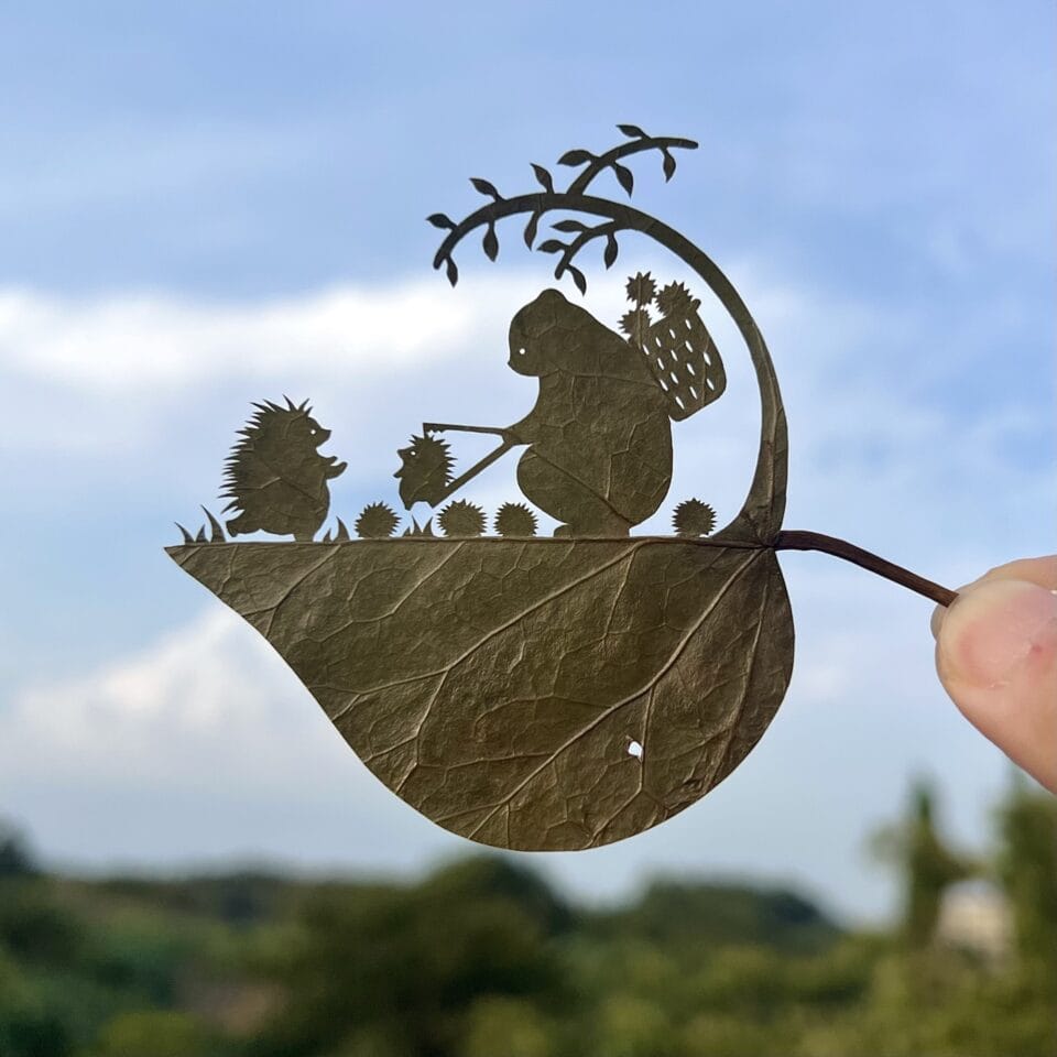 a cut leaf artwork of a bear and a hedgehog by a tree