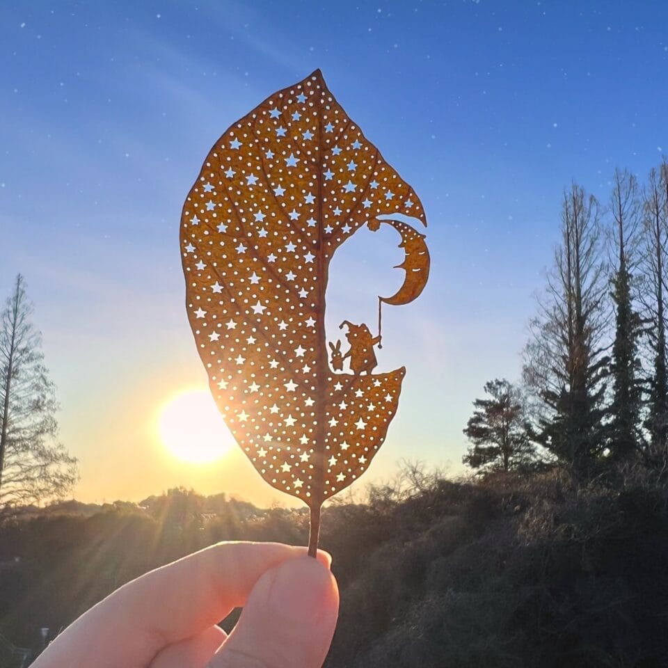 a cut leaf artwork of an animal and the moon against a starry sky